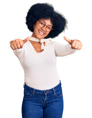 Wall Mural - Young african american girl wearing casual clothes and glasses approving doing positive gesture with hand, thumbs up smiling and happy for success. winner gesture.