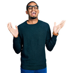 Poster - Young african american man wearing casual clothes and glasses celebrating crazy and amazed for success with arms raised and open eyes screaming excited. winner concept