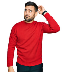 Poster - Young hispanic man wearing casual clothes confuse and wondering about question. uncertain with doubt, thinking with hand on head. pensive concept.