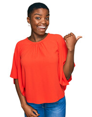 Wall Mural - Young african american woman wearing casual clothes smiling with happy face looking and pointing to the side with thumb up.