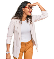 Canvas Print - Young african american girl wearing business clothes very happy and smiling looking far away with hand over head. searching concept.