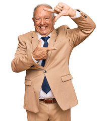 Canvas Print - Senior caucasian man wearing business suit and tie smiling making frame with hands and fingers with happy face. creativity and photography concept.