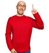 © Krakenimages.com - Bald man with beard wearing casual clothes and glasses pointing finger up with successful idea. exited and happy. number one.