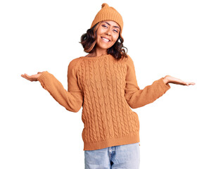 Young beautiful mixed race woman wearing wool sweater and winter hat smiling showing both hands open palms, presenting and advertising comparison and balance