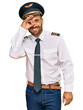 © Krakenimages.com - Handsome man with beard wearing airplane pilot uniform doing ok gesture with hand smiling, eye looking through fingers with happy face.