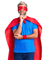 Poster - Young blond man wearing super hero custome looking confident at the camera with smile with crossed arms and hand raised on chin. thinking positive.