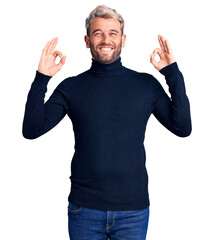 Sticker - Young handsome blond man wearing casual turtleneck sweater relax and smiling with eyes closed doing meditation gesture with fingers. yoga concept.