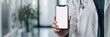 © olga_demina - Doctor holding smartphone with blank screen in modern clinic. Medical professional displaying phone mockup for healthcare application or service.