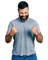 Wall Mural - Hispanic man with beard wearing casual grey t shirt celebrating surprised and amazed for success with arms raised and eyes closed