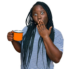 Poster - Young black woman with braids drinking a cup coffee covering mouth with hand, shocked and afraid for mistake. surprised expression