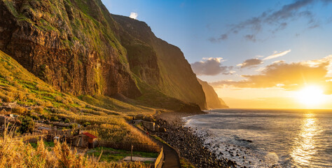 Wall Mural - Volcanic rock cliffs Achadas da Cruz in backlit sunlight. Waves of the Atlantic Ocean. Beautiful sunset seascape of the resort island of Madeira, Portugal