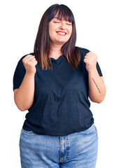 Poster - Young plus size woman wearing casual clothes excited for success with arms raised and eyes closed celebrating victory smiling. winner concept.