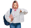 © Krakenimages.com - Hispanic woman with pink hair wearing student backpack and headphones pointing down with fingers showing advertisement, surprised face and open mouth