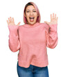 © Krakenimages.com - Hispanic woman with pink hair wearing casual winter sweater celebrating crazy and amazed for success with arms raised and open eyes screaming excited. winner concept