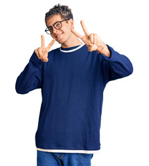 Wall Mural - Young handsome man wearing casual clothes and glasses smiling looking to the camera showing fingers doing victory sign. number two.