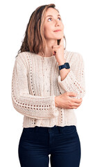 Wall Mural - Young beautiful blonde woman wearing casual sweater with hand on chin thinking about question, pensive expression. smiling and thoughtful face. doubt concept.