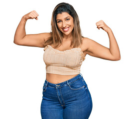 Poster - Beautiful brunette woman wearing casual clothes showing arms muscles smiling proud. fitness concept.