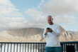 © ADDICTIVE STOCK - Man using smartphone with mountainous coastal backdrop