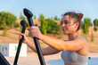 © ADDICTIVE STOCK - Young woman exercising on outdoor fitness equipment