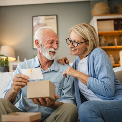 Senior husband read greeting card from a gift with his mature wife