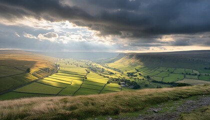 Wall Mural - dramatic landscape photograph of a sun drenched valley wrapped by heavy storm clouds with fields and hilly greenery under a dark sky yorkshire dales uk