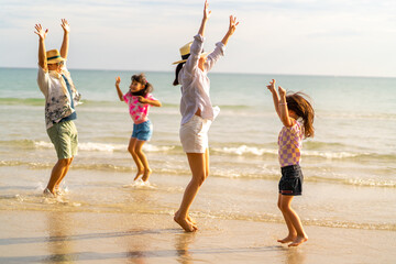 Wall Mural - Happy Asian family enjoy and fun outdoor lifestyle travel at the sea on summer beach holiday vacation. Father, mother and child girl kids walking and playing together on tropical beach at sunset.