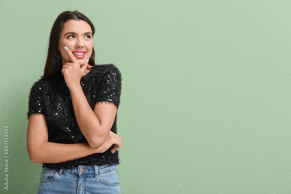 Beautiful young thoughtful woman on green background