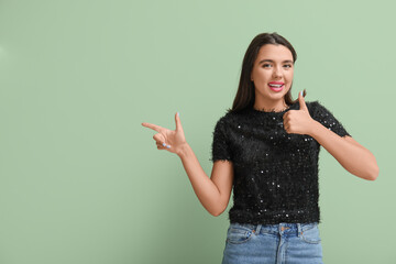 Canvas Print - Beautiful young happy woman pointing at something on green background