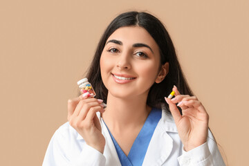 Happy smiling young female doctor with pills on beige background