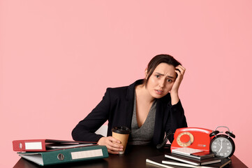 Poster - Stressed businesswoman at table on pink background. Concept of overwork and deadline