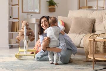 Sticker - Beautiful young happy mother hugging her cute little baby with different toys at home