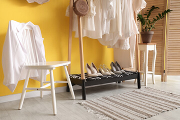 Wall Mural - Rack with white clothes near yellow wall in room