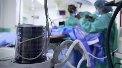 Wall Mural - Lung ventilator pump works in the surgery room. Close up. Doctor and scrub nurse operate the patient at backdrop in blur.