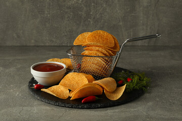 Potato chips with sauce and chili pepper on a dark background