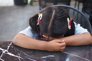 A girl with pigtails rests on a marble table, showing a serene moment of contemplation