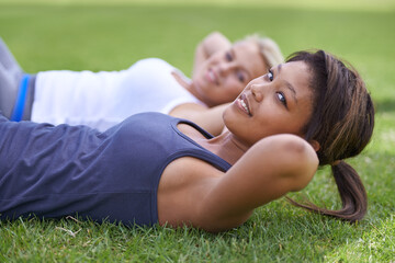 Happy woman, portrait and sit ups for outdoor exercise or workout in fitness together on green grass. Young active female person or people smile for training, health and wellness on field in nature