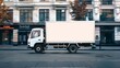 © RM Graphics - Empty blank white mockup on the small truck vehicle driving through the city street