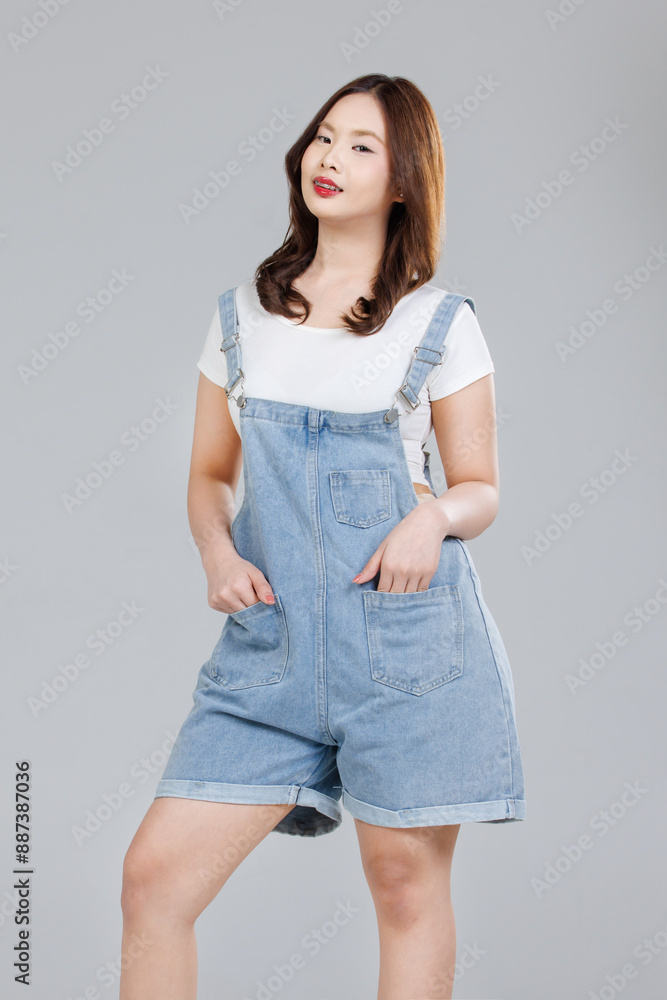 Portrait of Asian cute cheerful young girl wearing denim overalls ...