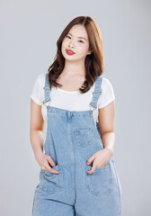 Wall Mural - Portrait of Asian cute cheerful young girl wearing denim overalls, stylish model woman with happy and cool sweet smile standing posing isolated on white background, Teenage and youth fashion.