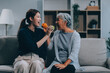 © ARMMY PICCA - Happy asian woman daughter hugging senior mother in the kitchen room eating healthy food happy enjoying.