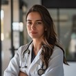 © TheVisualEngineer - Female doctor in a modern clinic looking at the camera with a confident expression.