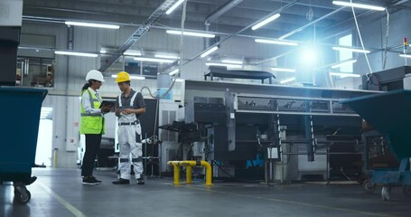 Leinwandbilder - Female Industrial Engineer Having a Conversation with a Young Asian Technician at a Manufacturing Plant. Colleagues Using a Tablet Computer, Discussing Production Numbers and Specifications