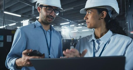Leinwandbilder - Two Male and a Female Factory Employees Standing in a High Tech Manufacturing Facility, Discussing Operations and Production Machinery. Diverse Employees Wear Safety Gear and Use a Laptop Computer