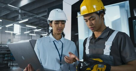 Aufkleber - Two Diverse Employees Talking in an Industrial Factory Hall. Female Engineer Using a Laptop, Explaining the Scope of Work to a Young Asian Technician. Workers Wearing Hard Hats for Safety