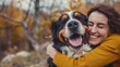 © robfolio - Woman Hugging Happy Bernese Mountain Dog Outdoors