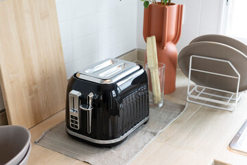 Bread toaster on kitchen worktop with tiled walls