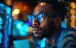 © imagineRbc - A young black man wearing glasses sits in front of a computer screen, looking intently at the artificial intelligence software displayed on the monitor