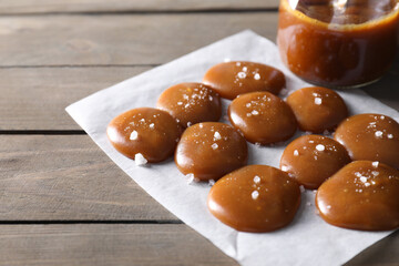 Wall Mural - Tasty candies, caramel sauce and salt on wooden table, closeup