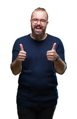 Wall Mural - Young caucasian hipster man wearing sunglasses over isolated background approving doing positive gesture with hand, thumbs up smiling and happy for success. Looking at the camera, winner gesture.