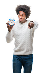 Canvas Print - Afro american man holding vintage alarm clock over isolated background pointing with finger to the camera and to you, hand sign, positive and confident gesture from the front